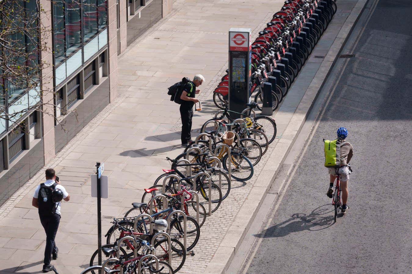 A cyclist unlocks his bike on Silk Street in the City of London, the capital's financial district, on 8th April 2025, in London, England. (Photo by Richard Baker / In Pictures via Getty Images)