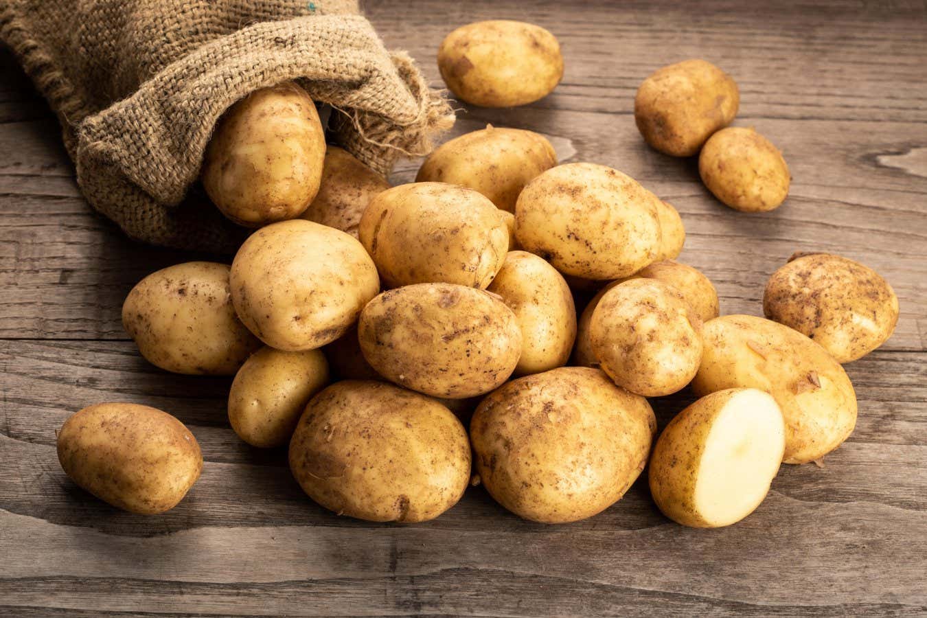 T8GENK Fresh new potatoes on wooden background. Solanum tuberosum